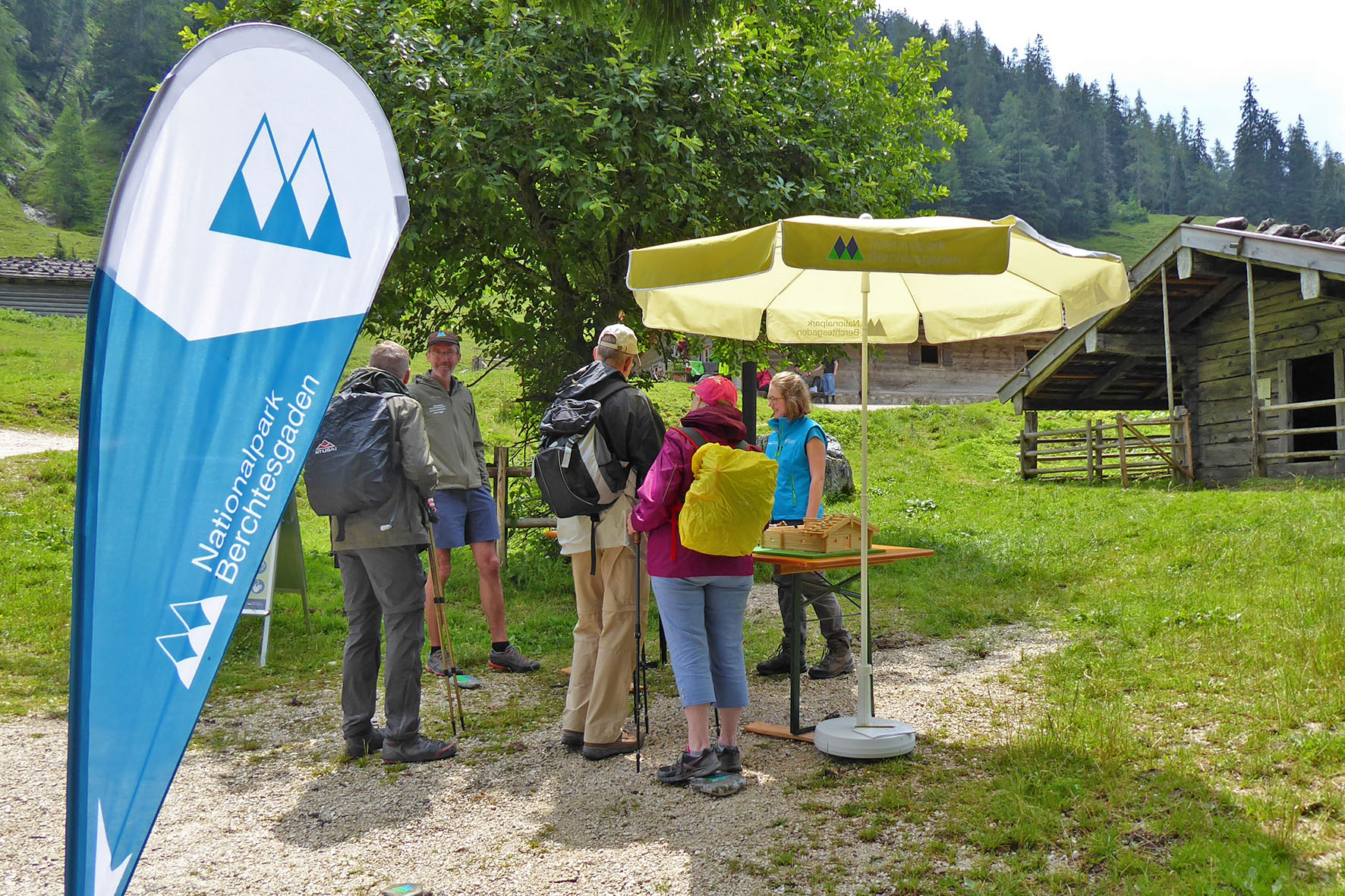 Pressebild: Neues, mobiles Bildungsangebot des Nationalparks Berchtesgaden im Klausbachtal: Auf der Bindalm informieren Nationalpark-Mitarbeiterinnen und -Mitarbeiter über die Almwirtschaft, präsentieren an einem Modell den traditionellen Rundum-Kaser und stellen die Pflanzenvielfalt auf Almen vor.